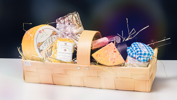 Geschenkkorb mit verschiedenen Esswaren wie Käse, Konfitüre und Wein. Der Geschenkkorb ist Beispiel für eine Sachspende.