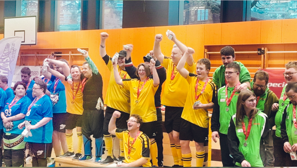 Das Unihockeyteam Lotzwiler Chnebler steht im gelben Trikot auf dem Podest und jubelt.