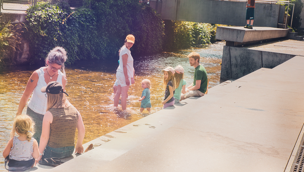 Gruppe von Teilnehmenden kühlen sich im Fluss die Füsse am Kinderfest von Procap Bern in Langenthal