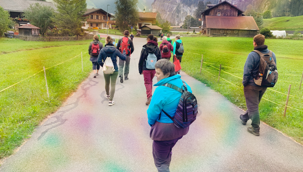 Gruppe von Menschen spaziert auf einer Landstrasse zwischen zwei Feldern