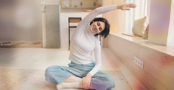Eine Frau, die am Boden sitzt und eine Dehnübung macht