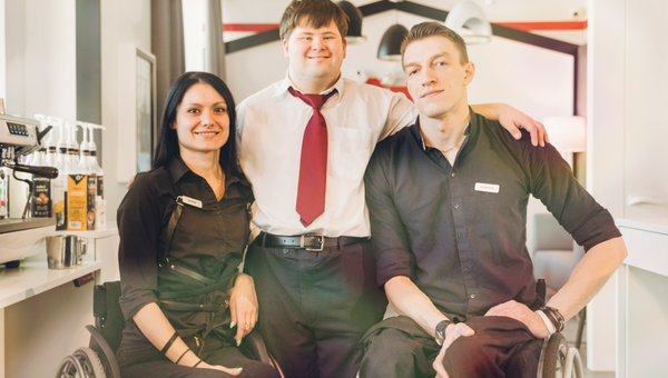 Gruppenbild von drei Personen, zwei davon im Rollstuhl